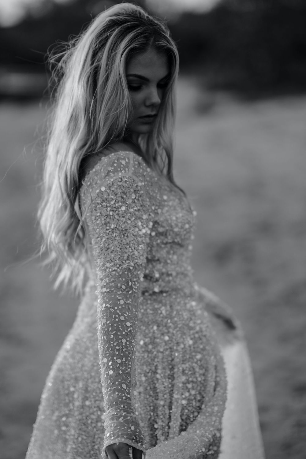 Black and white image of bride wearing sparkly bridal gown on the beach