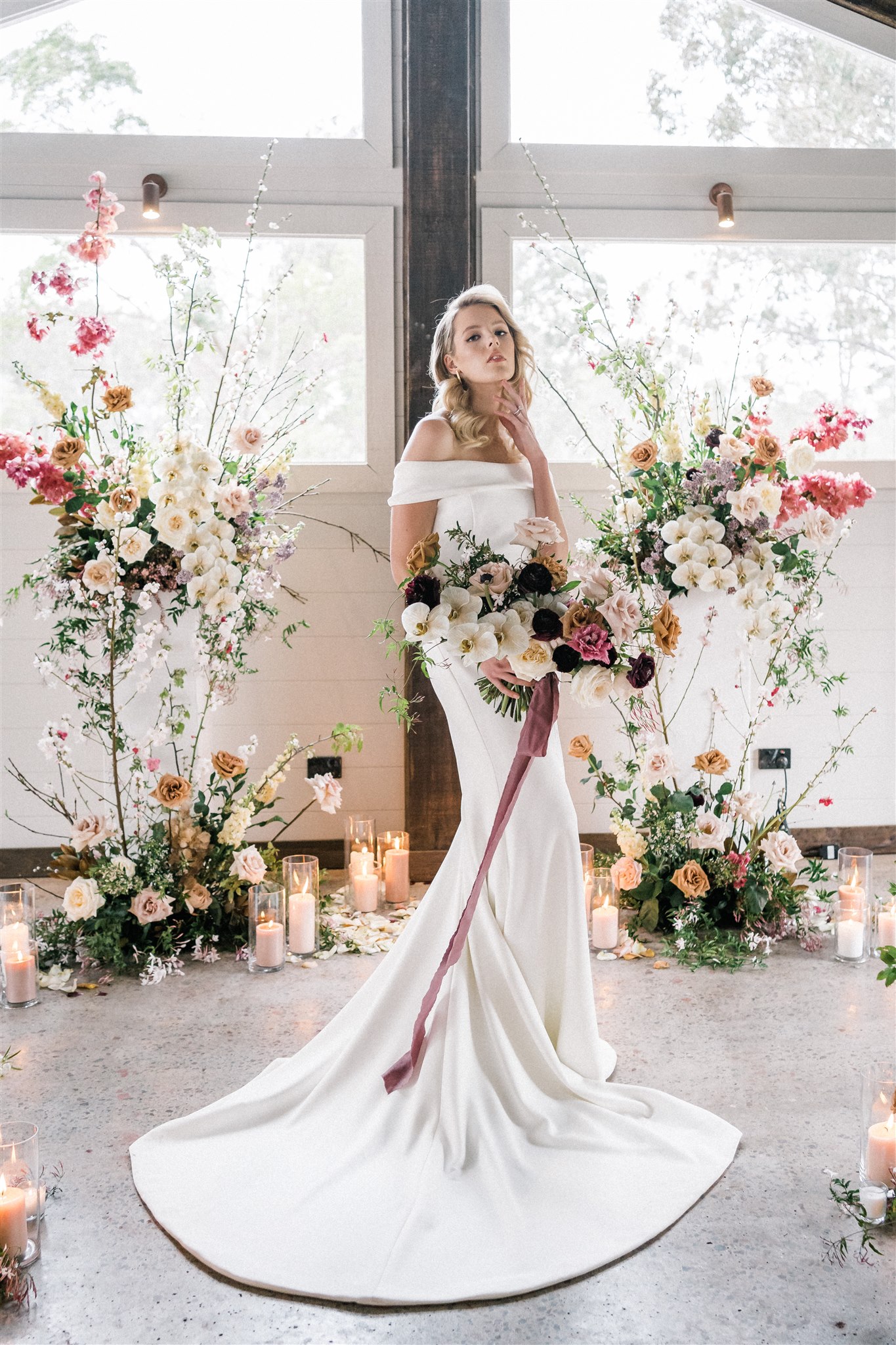 Bride holding pastel bridal bouquet surrounded by floral arrangements and candles — Sunshine Coast wedding flower inspiration and budget styling ideas