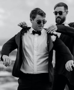 Groom and groomsman putting on suits