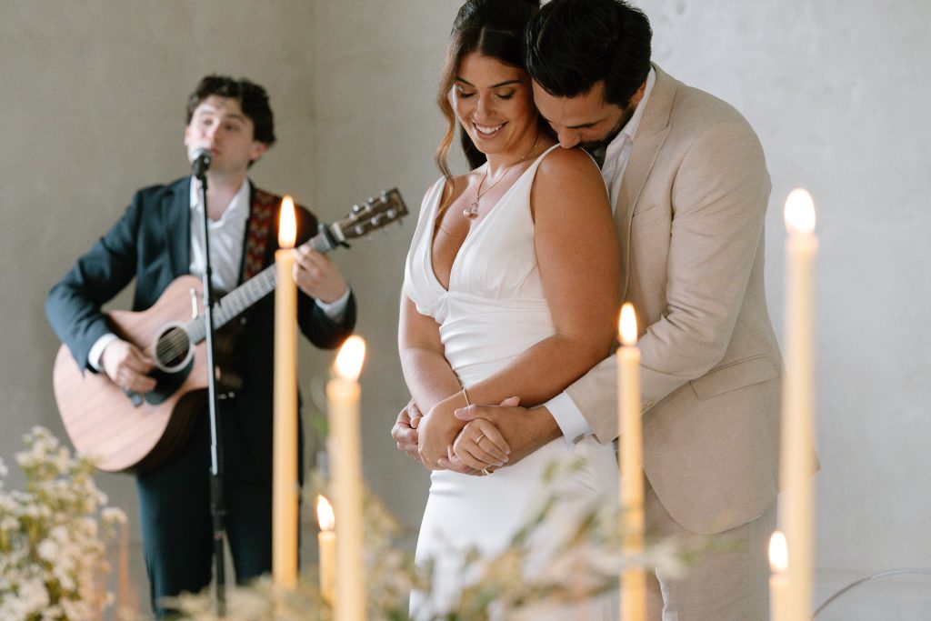 Just married couple dancing in the foreground by candlelight as acoustic guitarist and singer Harry Morris serenades at Sunshine Coast wedding Maleny