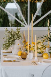 Wedding reception table decorated in various shades of yellow using flowers and candlees