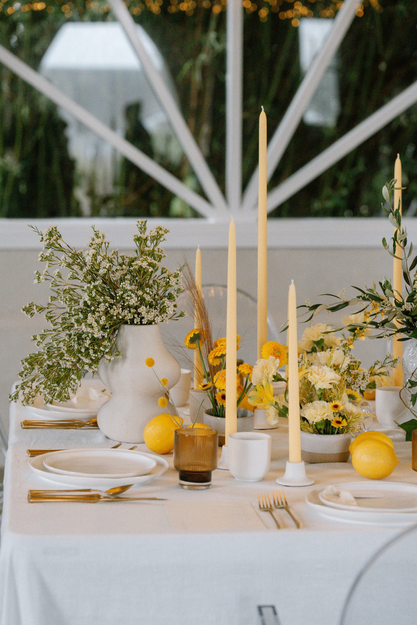 Wedding reception table decorated in various shades of yellow using flowers and candlees