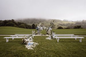 Ceremony styling with white bench seats and blue and white florals.