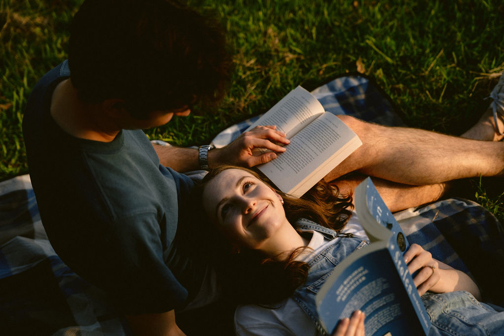 Happy couple just engaged reading in the park 