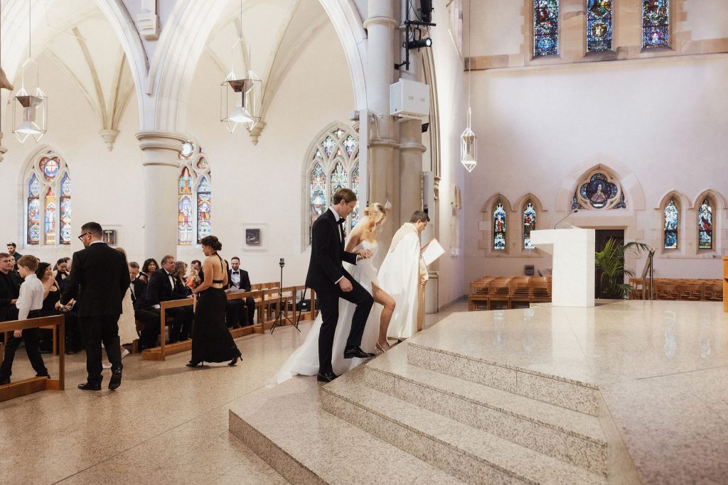 Bride and groom walking up steps of cathedral