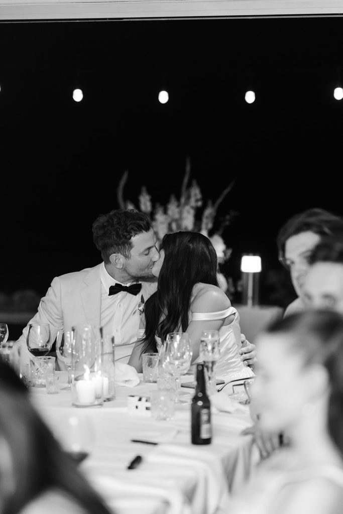 Black and white image of bride and groom kissing at their wedding reception in Noosa