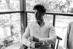 black and white image of groom sitting in luxury bridal suite cabin at Yandina Station on the Sunshine Coast