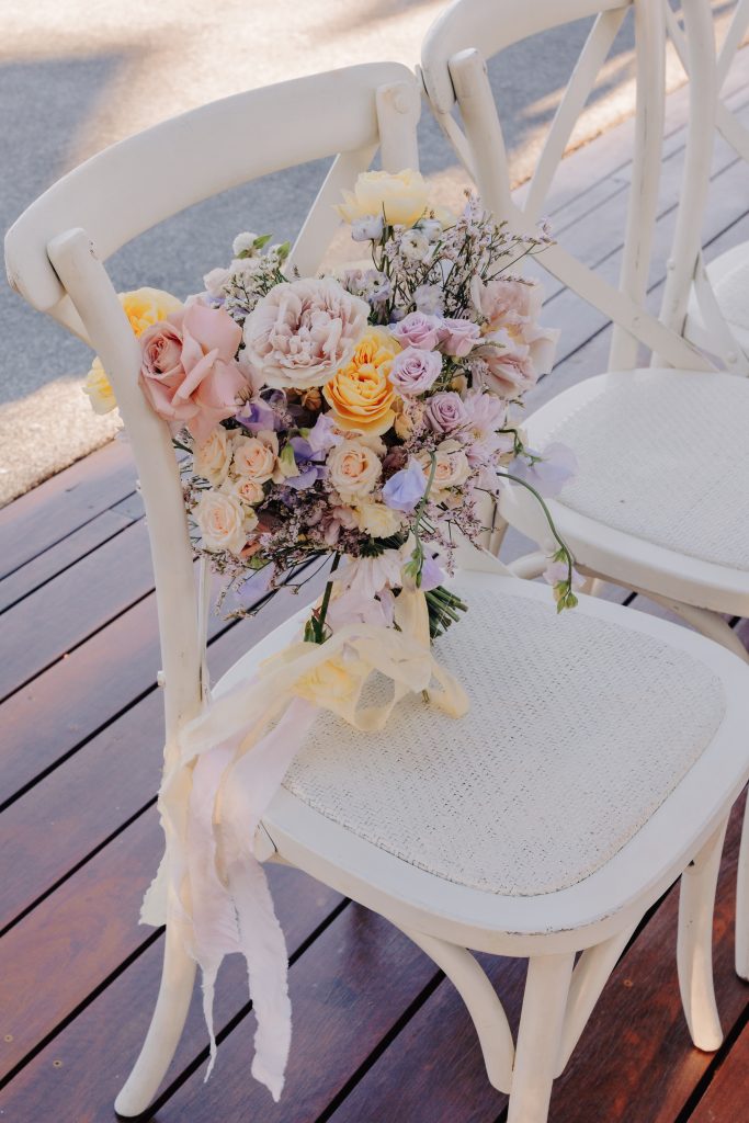 bridal bouquet on white hamptons style chair at wedding ceremony on the sunshine coast