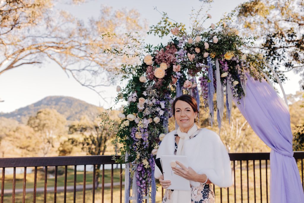 sunshine coast wedding celebrant philippa holness at yandina station wedding ceremony under lavender floral arbour with draped fabric