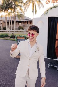 groom trying on funny prop sunglasses at vintage caravan photo booth sunshine coast