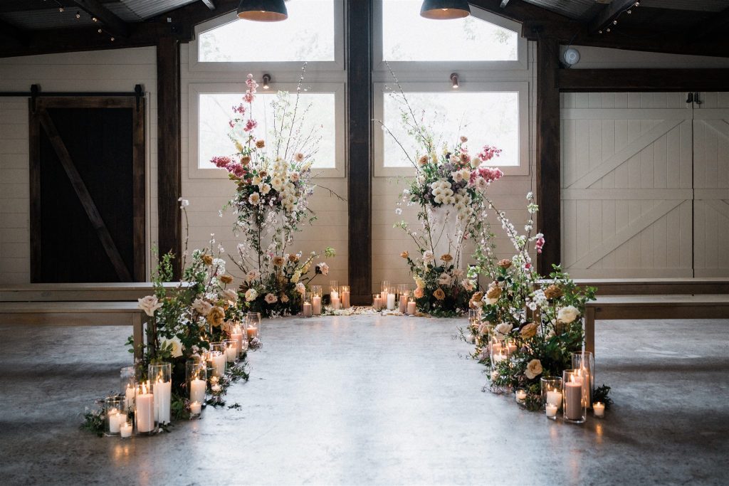 Luxury indoor wedding ceremony flower arrangements with candles and pastel blooms by a Sunshine Coast florist